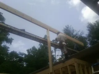 Carpenter setting a ridge beam over a new addition frame — Ice Dam Removal by Roofing Brothers in Speonk