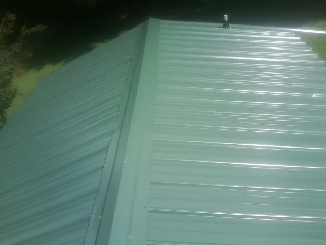 New green metal panels meeting at the ridge of a roof — Flat Roof Repair work by our crew in Speonk