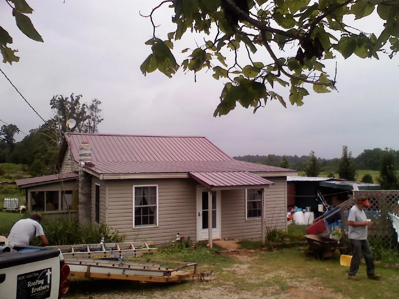 Crew finishing a mauve metal roof on a small farmhouse in Speonk