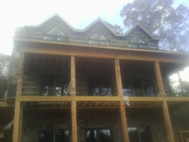 Dormers and porch framing on a large log home under construction — Roof Coating work by our crew in Speonk