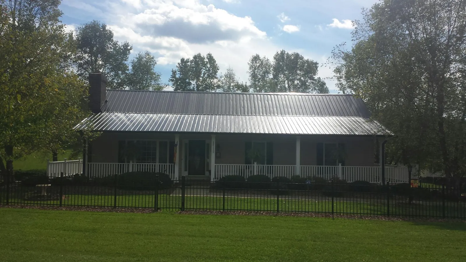 Gray metal roof on a brick ranch with a full width front porch — Gutter Guard Installation work by our crew in Speonk