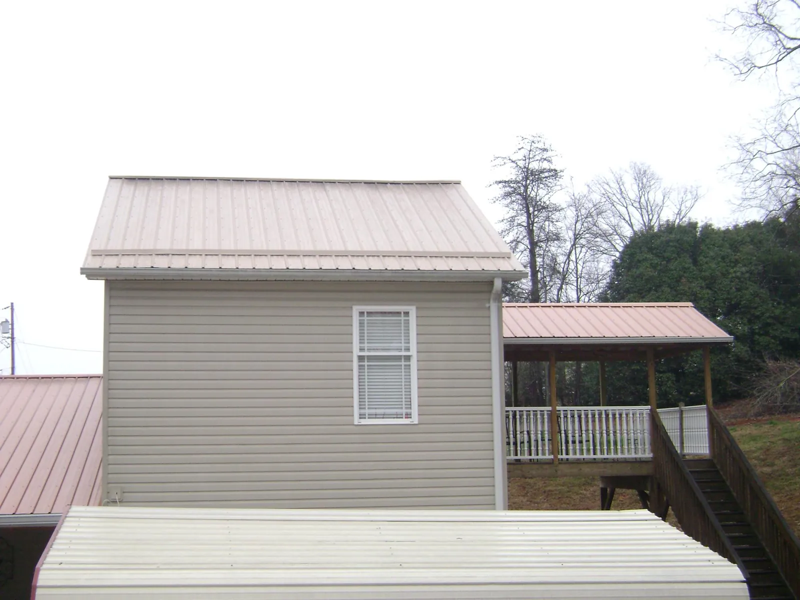 Tan metal roofs on a two story addition and attached porch, from a Roof Replacement job in Speonk