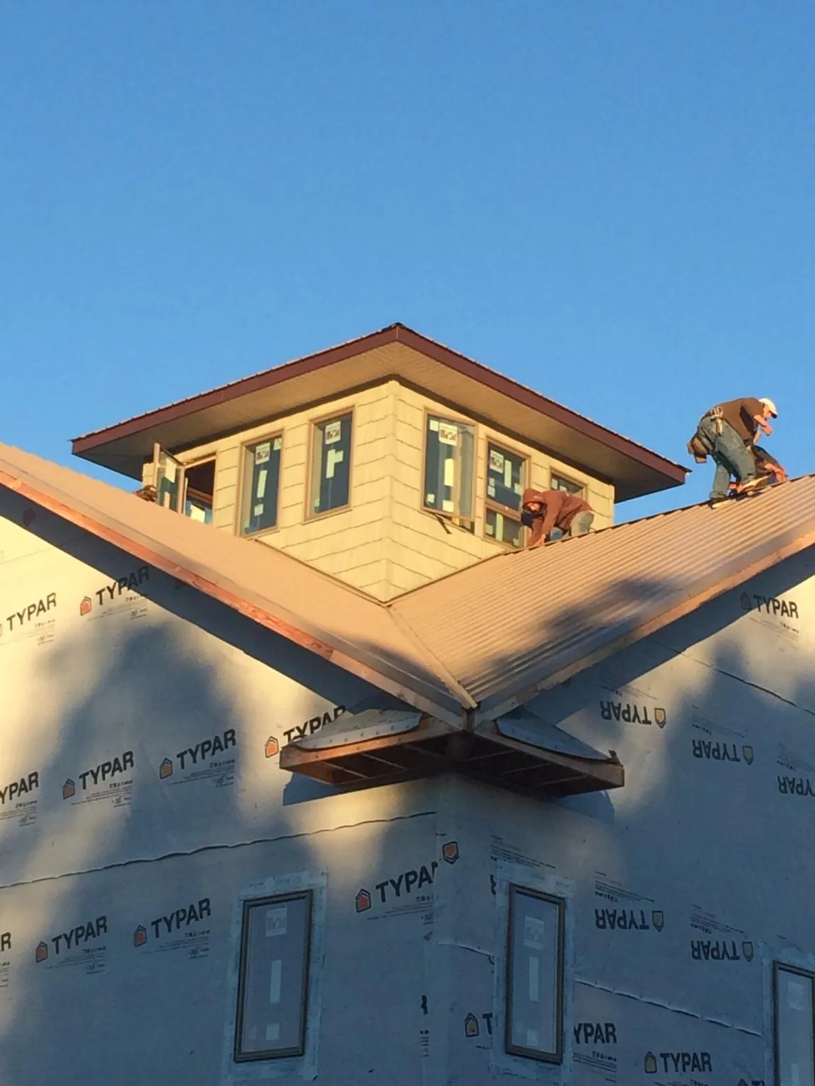 Roofers working around a rooftop cupola on a new metal roof at sunset — Roof Waterproofing in Speonk by Roofing Brothers